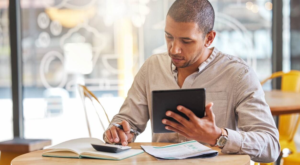 Man working on accounts with calculator.