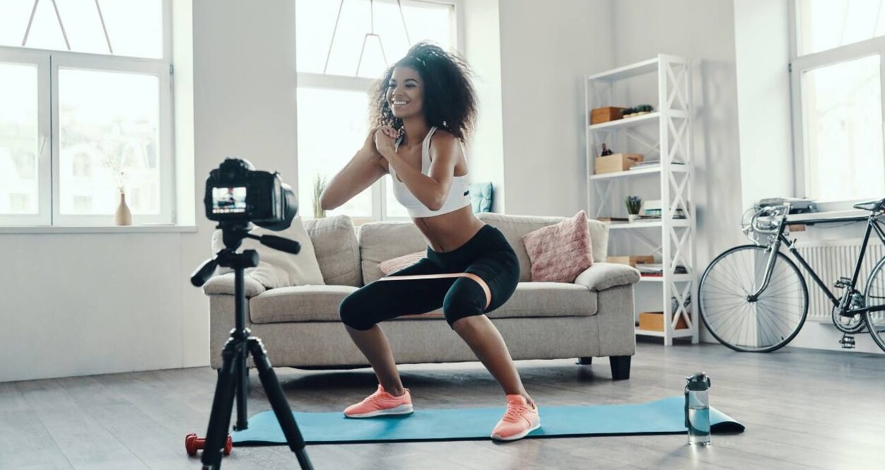 Woman online fitness training in living room with camera